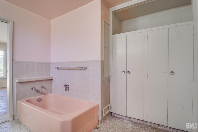 bathroom featuring a tub to relax in and tile walls