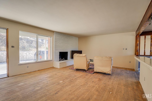 unfurnished living room with light hardwood / wood-style floors and a brick fireplace