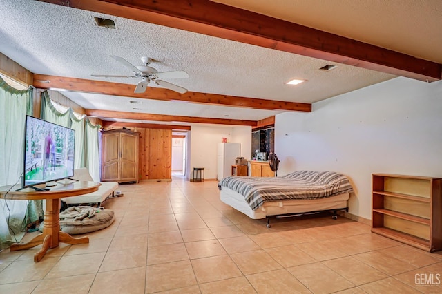 bedroom with ceiling fan, beamed ceiling, light tile patterned floors, and a textured ceiling