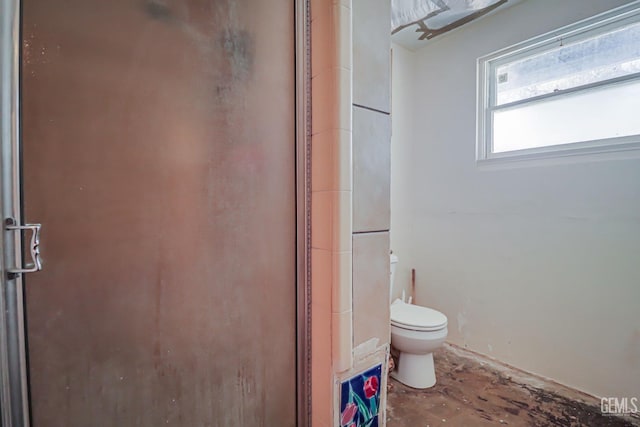 bathroom featuring toilet and a shower with shower door