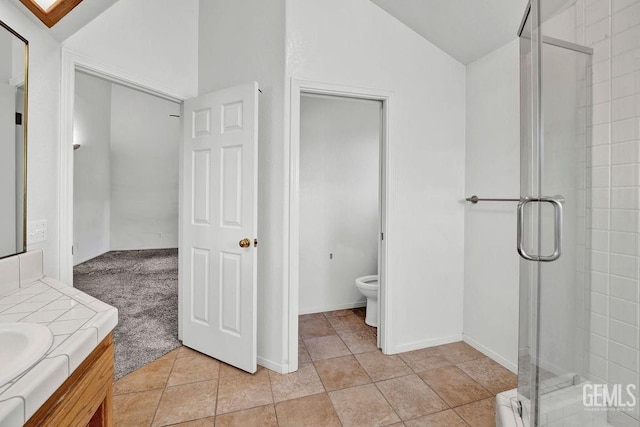 bathroom featuring toilet, vaulted ceiling, vanity, and a stall shower