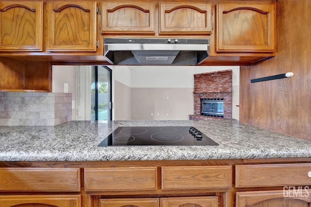 kitchen with black electric cooktop, under cabinet range hood, and brown cabinetry
