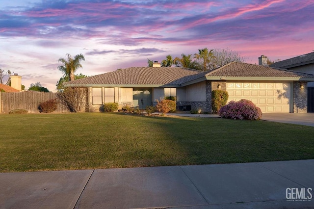 ranch-style house featuring fence, a tiled roof, an attached garage, a chimney, and a yard
