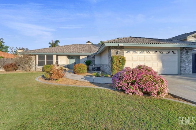 ranch-style home featuring a tile roof, concrete driveway, a front yard, a garage, and a chimney
