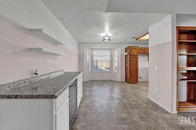 kitchen with light tile patterned floors, baseboards, open shelves, and stainless steel dishwasher