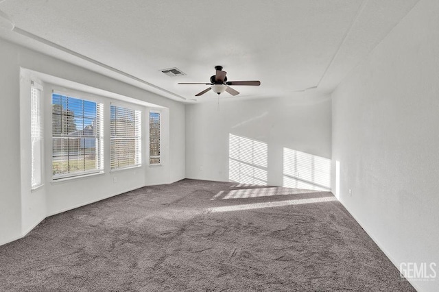 empty room featuring a ceiling fan, carpet floors, and visible vents