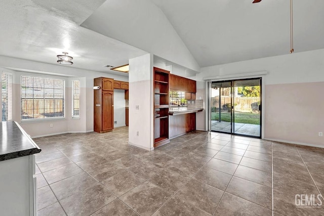unfurnished living room featuring tile patterned floors, high vaulted ceiling, and baseboards
