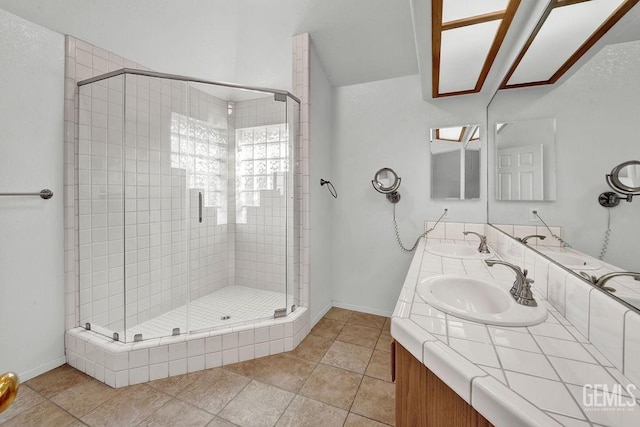 full bath featuring baseboards, double vanity, a sink, and a stall shower