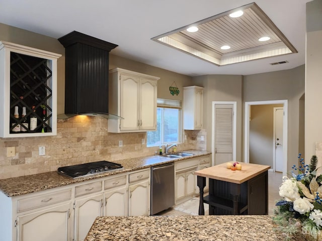 kitchen featuring sink, wall chimney exhaust hood, decorative backsplash, a tray ceiling, and stainless steel appliances