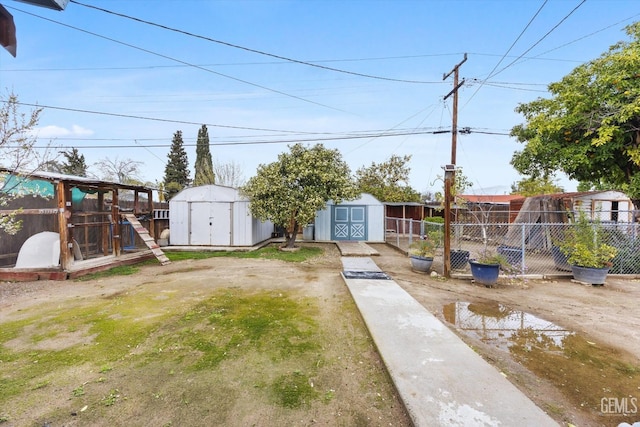 view of yard featuring a storage shed, an outbuilding, and fence