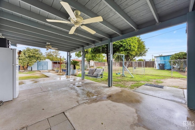 view of patio featuring a playground, a storage shed, a fenced backyard, an outbuilding, and a ceiling fan