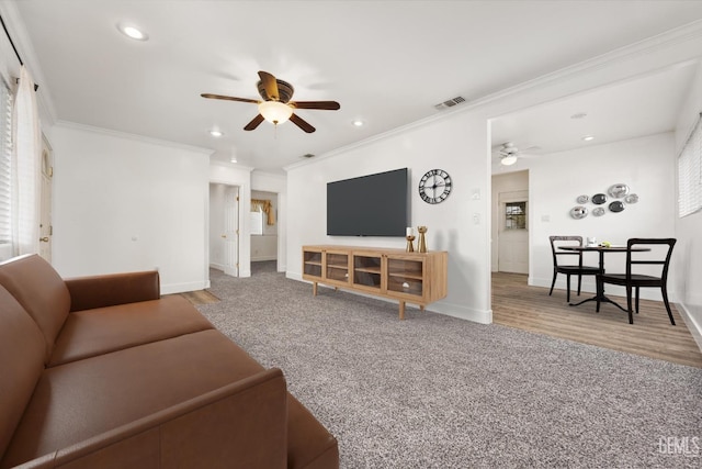 living room with visible vents, ornamental molding, ceiling fan, and carpet floors