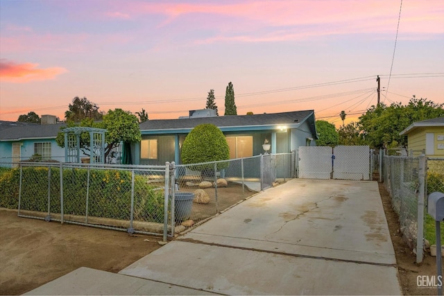 view of front facade with concrete driveway, a gate, and a fenced front yard