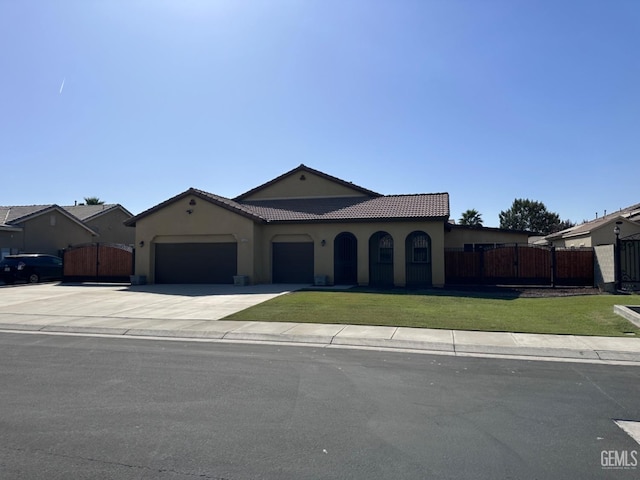 mediterranean / spanish-style home featuring a garage and a front lawn