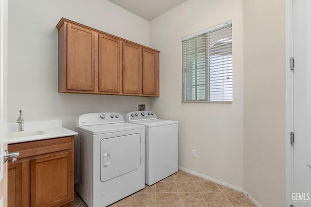 laundry room featuring washing machine and clothes dryer, baseboards, a sink, and cabinet space
