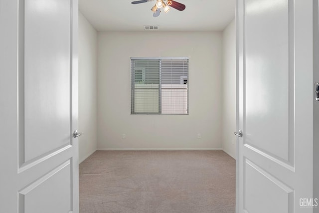 carpeted empty room with a ceiling fan, baseboards, and visible vents