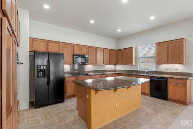 kitchen with dark stone countertops, black appliances, recessed lighting, a kitchen bar, and a kitchen island