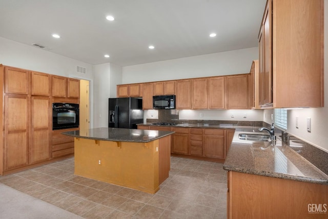 kitchen with a sink, dark stone countertops, black appliances, a breakfast bar area, and a center island