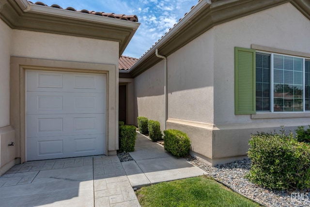 view of home's exterior featuring a tiled roof, stucco siding, driveway, and a garage