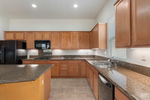 kitchen with black appliances, dark stone counters, a sink, and a wealth of natural light