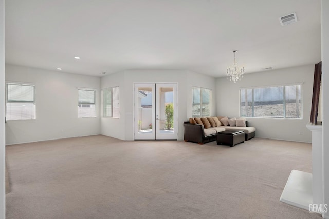 living room featuring an inviting chandelier, a wealth of natural light, carpet flooring, and visible vents