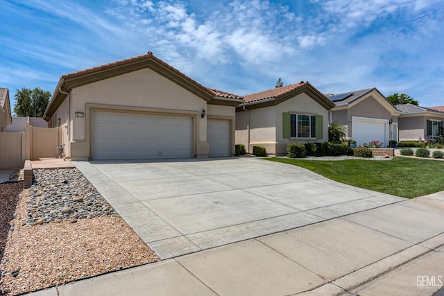 view of front of property with an attached garage, a tiled roof, stucco siding, fence, and driveway