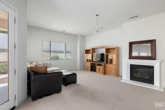 living room featuring light colored carpet, visible vents, a glass covered fireplace, and a notable chandelier