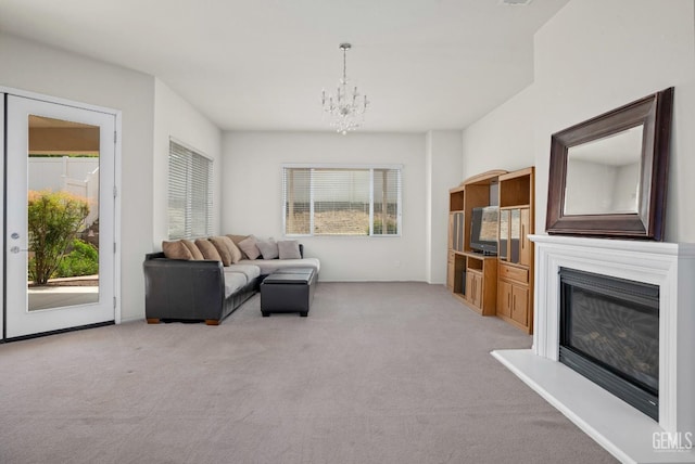 living room with light colored carpet, a notable chandelier, and a glass covered fireplace