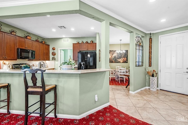 14030 Sandstone Peak Dr, Bakersfield, CA 93306 - kitchen with black appliances, a peninsula, light countertops, brown cabinets, and a breakfast bar area