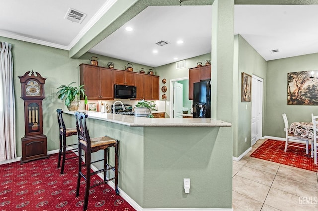 14030 Sandstone Peak Dr, Bakersfield, CA 93306 - kitchen featuring black appliances, a peninsula, brown cabinets, recessed lighting, and a kitchen breakfast bar