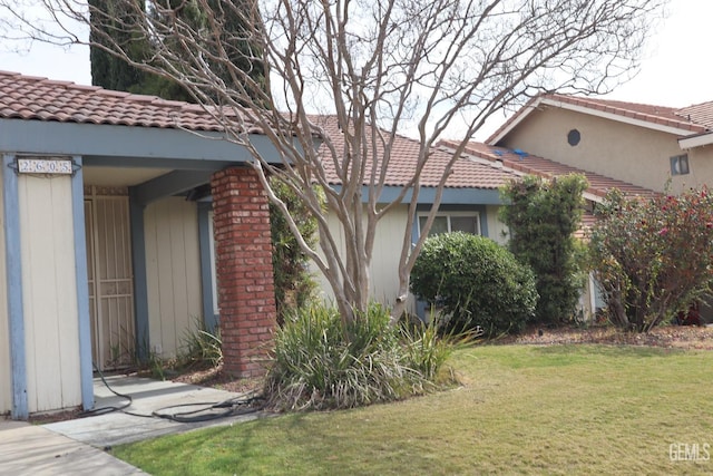 view of home's exterior with a tiled roof and a lawn