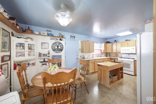 kitchen featuring white appliances, ceiling fan, sink, light brown cabinets, and a center island