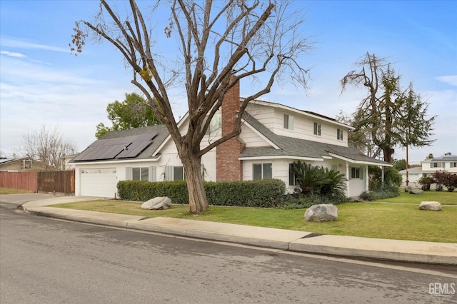 view of side of home with a garage, solar panels, a lawn, a chimney, and fence