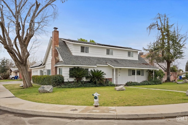 traditional home featuring driveway, a front lawn, a chimney, and roof mounted solar panels