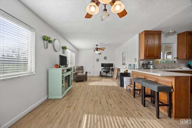 kitchen featuring light wood-style flooring, a breakfast bar area, light countertops, and a wealth of natural light