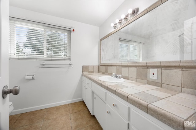 bathroom featuring backsplash, tile patterned flooring, vanity, and baseboards