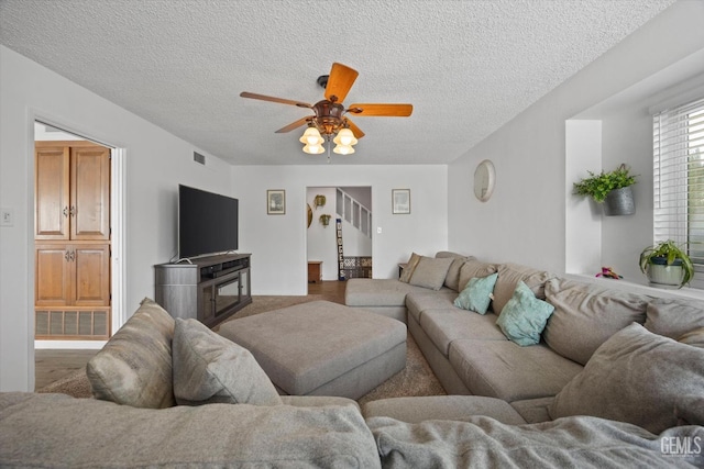 living room with stairway, a textured ceiling, visible vents, and a ceiling fan