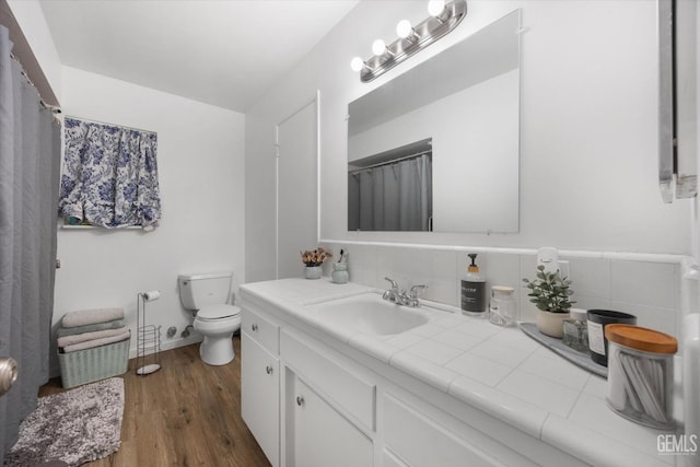 bathroom with vanity, backsplash, wood finished floors, and toilet