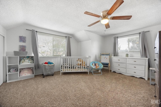 unfurnished bedroom with lofted ceiling, a crib, a textured ceiling, and carpet flooring