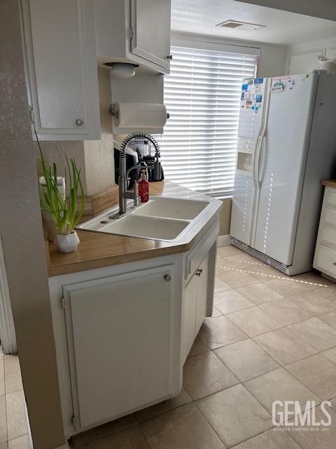 2626 E Cleo Ct Unit 29, Bakersfield, CA 93306 - kitchen featuring white refrigerator with ice dispenser, light tile patterned floors, white cabinetry, and light countertops