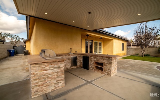 view of patio / terrace featuring ceiling fan, an outdoor kitchen, a grill, and sink