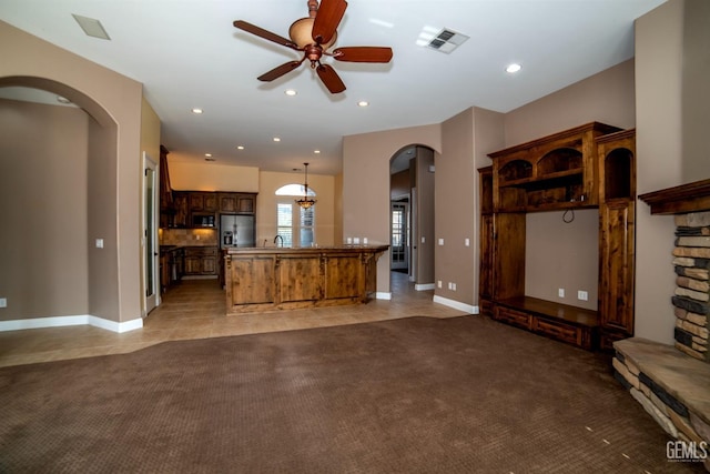 unfurnished living room featuring sink, ceiling fan, and carpet