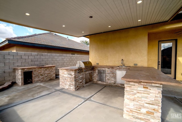 view of patio featuring an outdoor kitchen, area for grilling, and sink