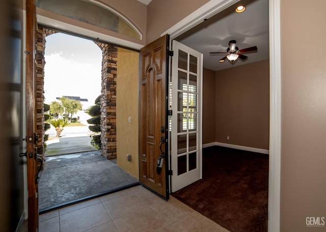 doorway featuring light tile patterned flooring and ceiling fan