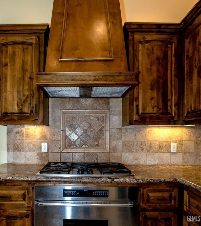 kitchen with stainless steel appliances, tasteful backsplash, dark stone countertops, and custom exhaust hood