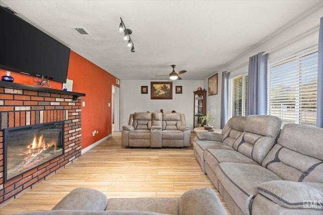 living room with ceiling fan, a fireplace, and rail lighting