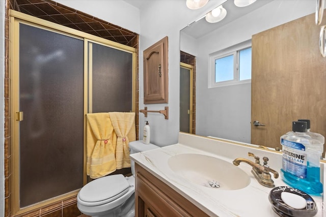 bathroom featuring a shower with door, vanity, and toilet