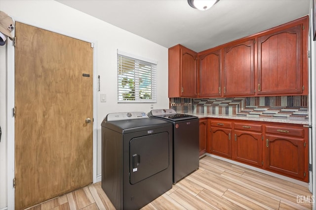 laundry room with cabinets, light hardwood / wood-style flooring, and washer and dryer