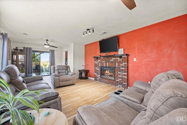 living room featuring rail lighting, ceiling fan, and a fireplace