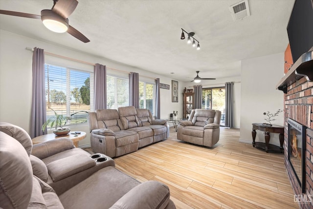 living room featuring a brick fireplace and ceiling fan